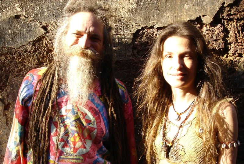 Gil and Ariane standing together in warm sunlight against an old stone wall